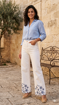 Pantaloni bianchi cropped a gamba larga con ricami floreali blu.